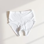 White high waisted black leggings seamless underwear folded neatly on a neutral surface, top-down view.