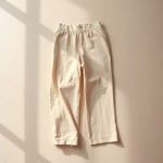 Flat lay of black wide leg yoga pants high waisted in beige, neatly folded on a neutral surface, minimalist e-commerce style.