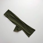 Neatly folded olive green black yoga pants flare legging in a minimalist flat lay.