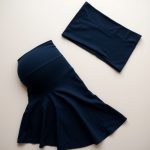 Flat lay of navy blue flare maternity leggings black sports skort folded neatly on a neutral surface.