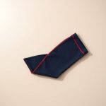 Flat lay of womens flare pants in red, the navy blue flare leggings folded on a neutral surface.