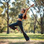A woman in charcoal high waisted yoga pants performing a yoga pose in an Australian park, flared leggings in motion.