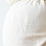 Close-up of linen fabric texture and stitching on a long sleeve maternity top and breastfeeding sports bra in Australia.