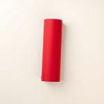 Flat lay of a red manduka mat, a travel yoga mat, folded neatly on a neutral surface.